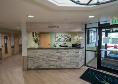 Reception area with stone-front desk, flowers, office equipment, and a landscape painting.